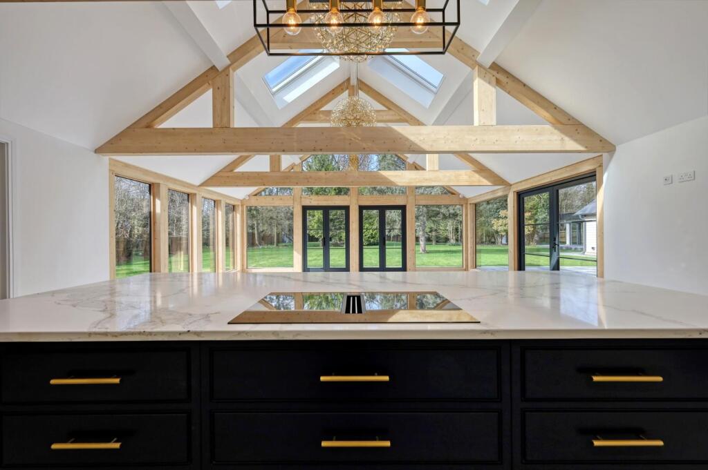 View across the dark kitchen island towards the glazed timber extension