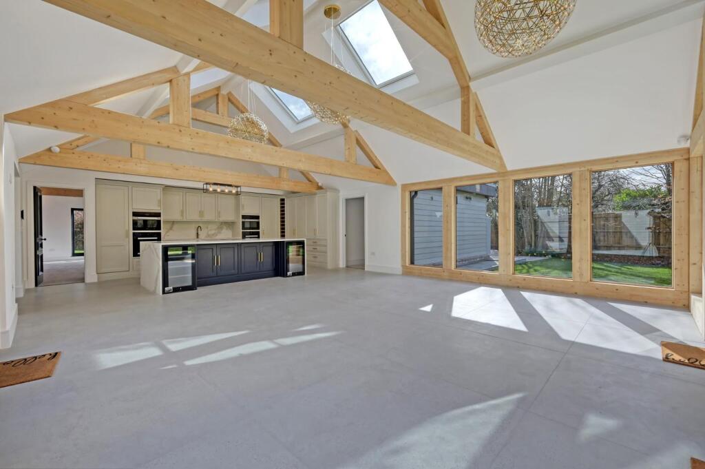 Vaulted kitchen and living space with painted bespoke cabinetry and a dark island